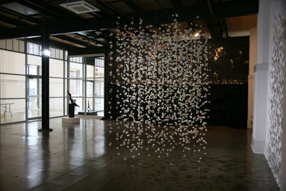 Installation artwork by Chintia Kirana of broken eggshells suspended on filament in a rectangular shape. 