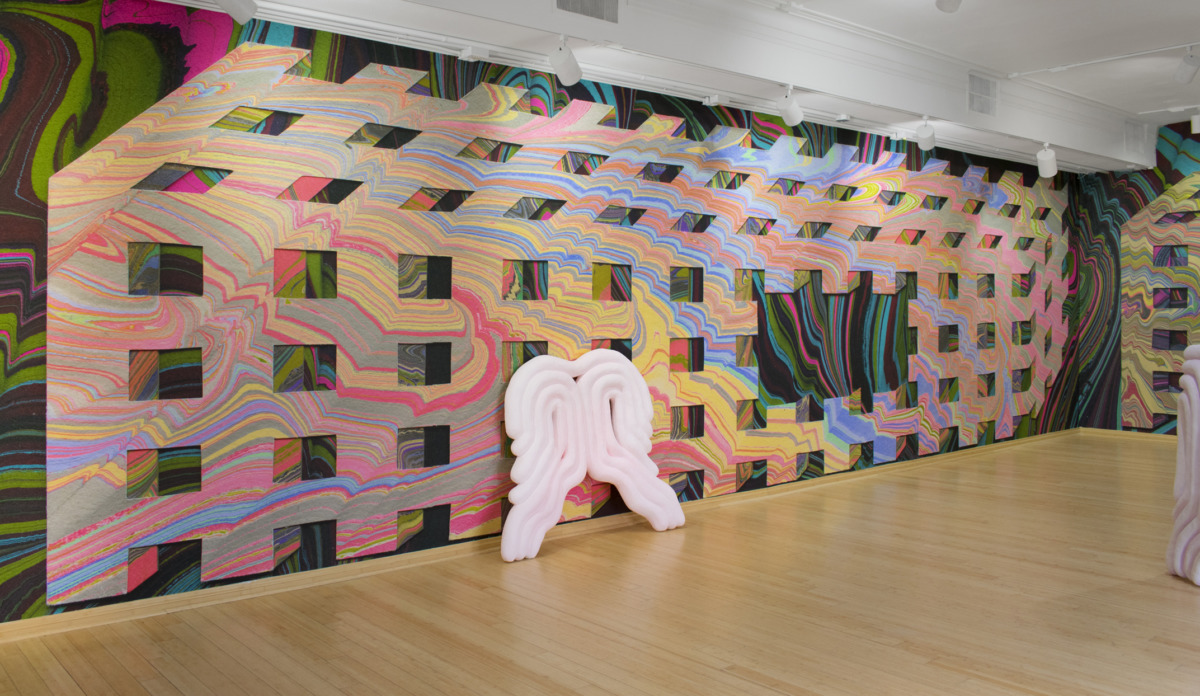 A curly white sculpture is tilted against a colorful gallery wall.