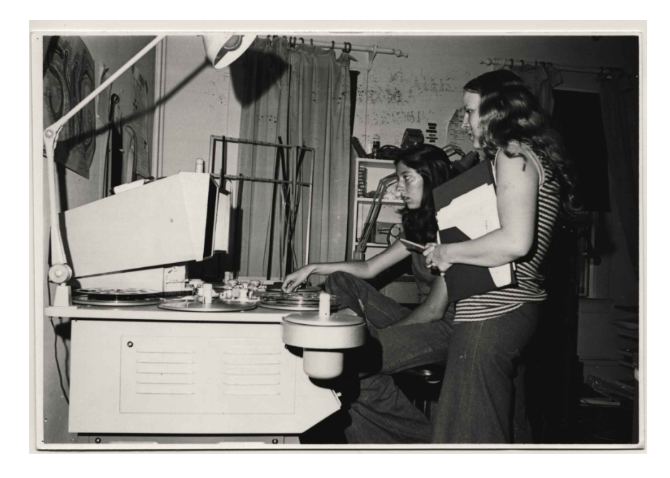 Two women look over a film editor in a vintage, archival photograph.