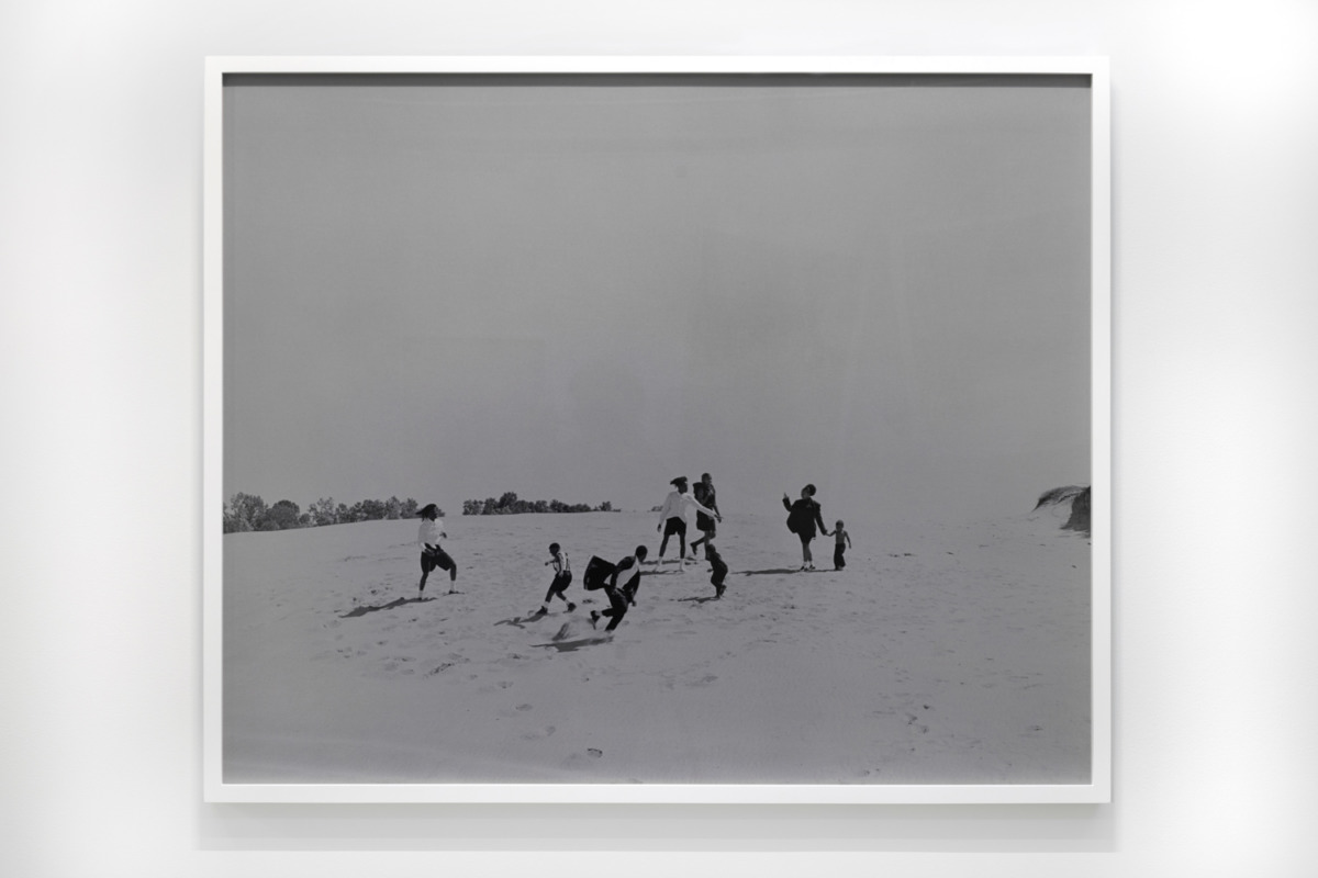 Black and white high contrast photograph of a family on a dune.