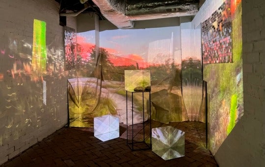 a video projected onto canvas, depicting a campfire scene at sunset