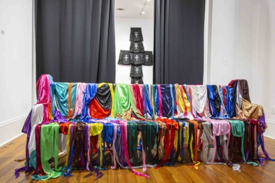 installation view of draped durags over a seat and a black and white installation piece in the background