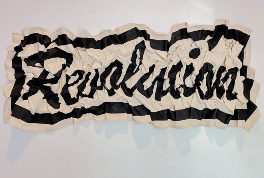 installation view of work spelling REVOLUCION on textiles