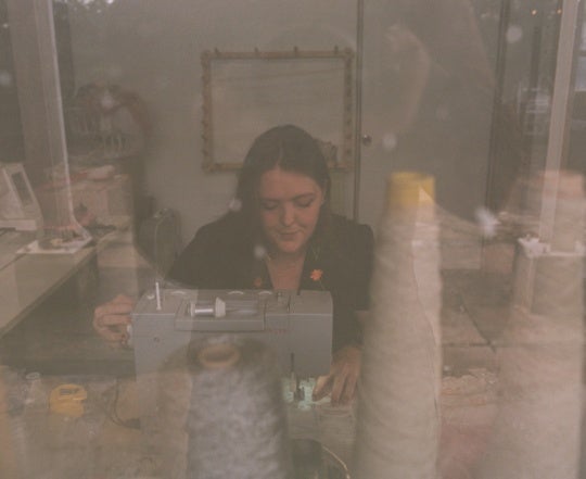 double exposure film still of white woman working behind a sewing machine