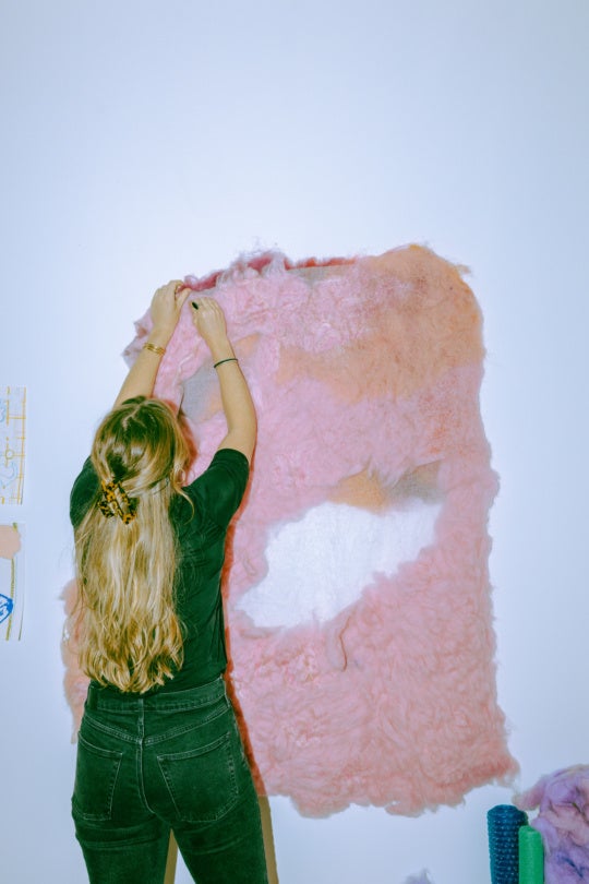 image of woman with her back facing the camera tugging at textile work